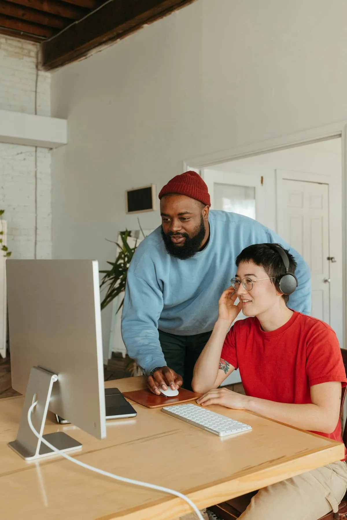 A colleague leaning over to help someone at their desk